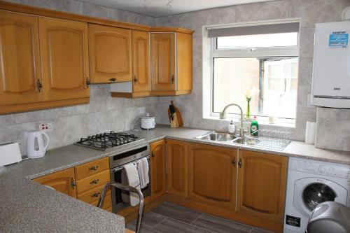 a kitchen with wooden cabinets and a sink at 25 Idmiston Road in London