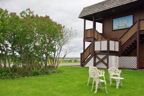 特魯羅的住宿－湧潮酒店，两把椅子和一张桌子,在一座建筑旁边的草丛里
