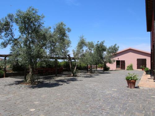 a courtyard with trees and a pink building at Farmhouse Montalto near Sandy Beaches in Montalto di Castro