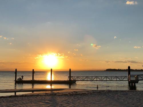 a sunset on the beach with a pier at Bribie Island Hotel in Bellara