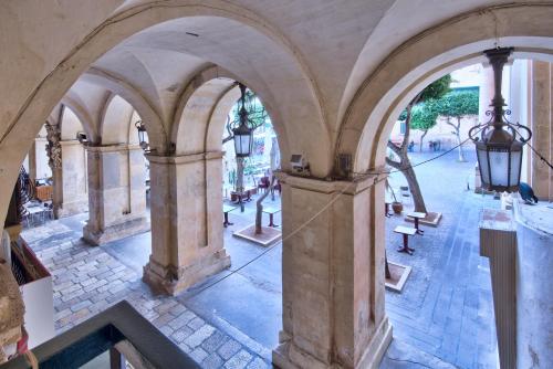 an archway in a building with tables and benches at U Collection - a Luxury Collection Suites, Valletta in Valletta