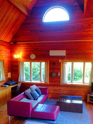 a living room with a red couch in a wooden house at Private Beach House in Motobu