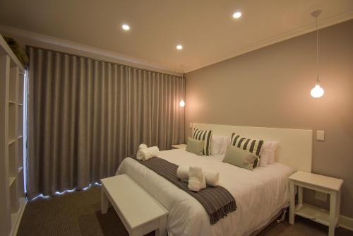 Un dormitorio con una gran cama blanca y una ventana en Willow Rest Villas en Clarens