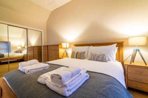 1 dormitorio con 1 cama grande y toallas. en Old Station Cottages en Aberfeldy