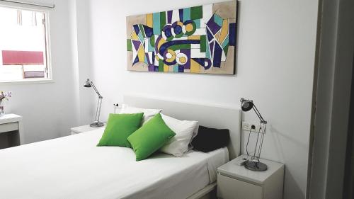 Un dormitorio con una cama con almohadas verdes y una pintura en CANARIAS. ISLAS AFORTUNADAS, en Las Palmas de Gran Canaria