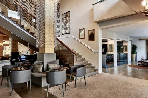 a lobby with a staircase and tables and chairs at Rouge Hotel International in Milano Marittima