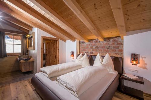 a large bed in a room with wooden ceilings at Chalet Apartment Obermanzl in Hopfgarten im Brixental