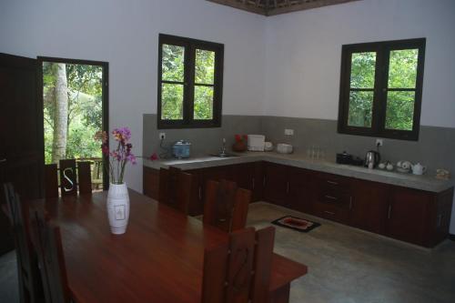 a kitchen with a wooden table with a vase of flowers on it at Villa Greenary in Unawatuna