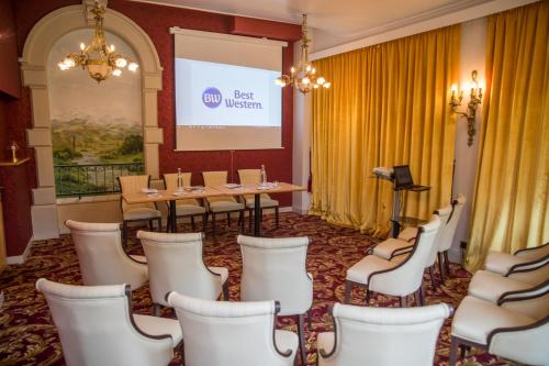 a conference room with a table and chairs and a screen at Best Western Beauséjour in Lourdes