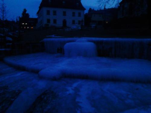 a snow covered yard at night with a house in the background at Jiřetínská chaloupka in Jiřetín pod Jedlovou