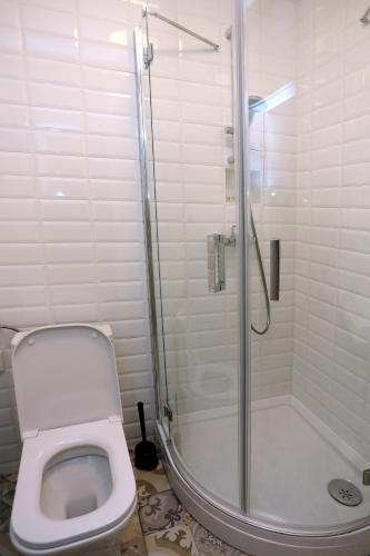 a bathroom with a shower with a toilet and a glass shower door at HOME APARTMANI I SOBE in Osijek
