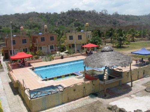 a large swimming pool with an umbrella and chairs at Hosteria Mar de Plata in Cabuyal