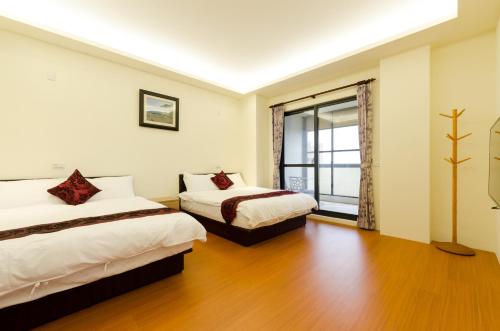 花蓮市にある9x9 Homestayのベッドが2つと窓があるホテルの部屋