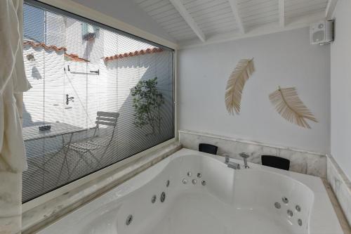 a white bath tub in a bathroom with a window at Sigacik Gardenya Buti̇k Otel in Siğacık