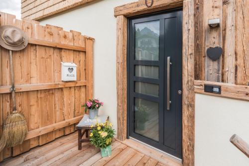 a black door on a wooden deck with flowers at Apartchalet Almliebe in Maria Alm am Steinernen Meer