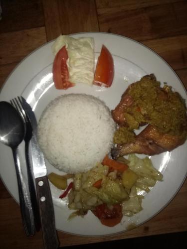 a white plate of food with rice and vegetables at Triangle House and hot spring in Kintamani