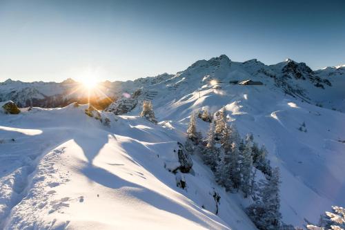 a snow covered mountain with the sun in the background at Haus Galgenul in Sankt Gallenkirch