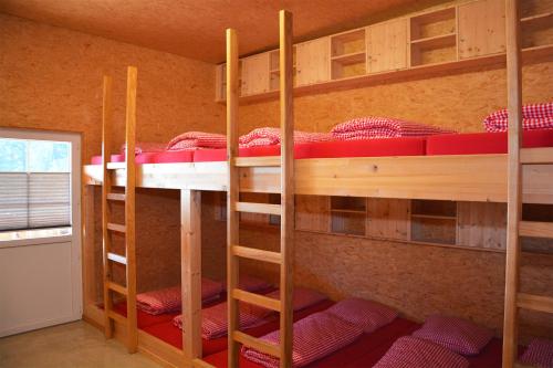 a room with three bunk beds with red blankets at Ribelhof in Altstätten