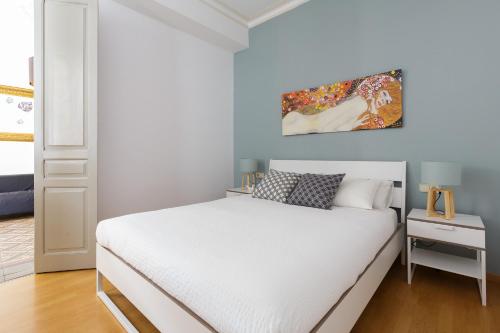 バルセロナにあるCasa Cosi - Mallorca 2の白いベッドと壁に絵画が飾られたベッドルーム1室