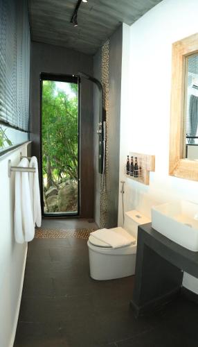 a bathroom with a toilet and a sink and a window at Pahili Pool Villas Koh Tao - SHA Plus in Koh Tao