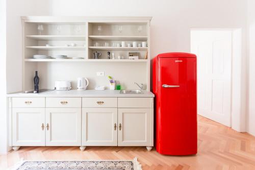 a red refrigerator in a kitchen with white cabinets at Barbo Palace Apartments and Rooms in Ljubljana