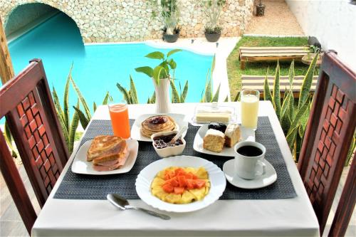 a table with breakfast food on it with a pool at Mayan Majesty Boutique Hotel in Valladolid