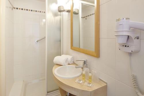 uma casa de banho com um lavatório e um chuveiro em Hôtel Vacances Bleues Villa Caroline em La Baule
