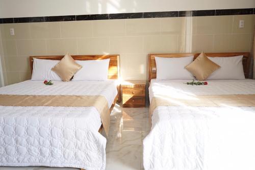 two beds in a room with white sheets and flowers at Hotel Hoai Anh in Vung Tau