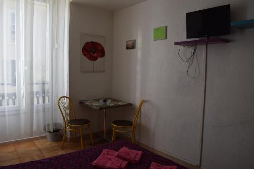 a room with a table and two chairs and a television at Résidence Appartement Adonis in Nice