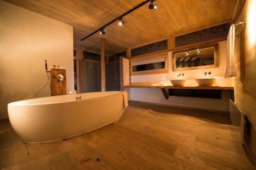 a bathroom with two sinks and a large tub at Les Mazots de la Source & Spa in Vercorin