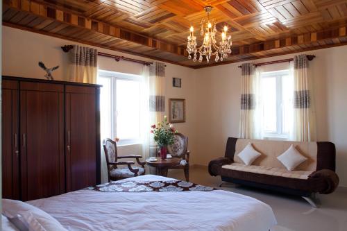 a bedroom with a bed and a couch and a chandelier at Villa Du Lac Da Lat in Da Lat