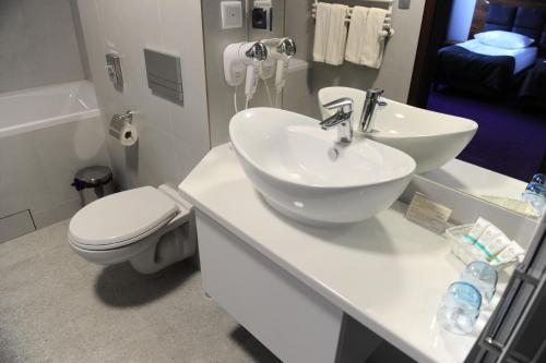 a bathroom with a white sink and a toilet at Best Western Plus Hotel Olsztyn Old Town in Olsztyn