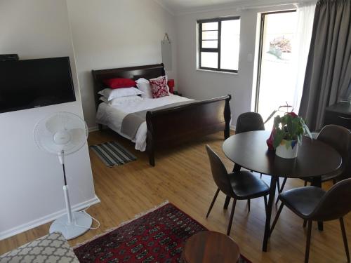 a bedroom with a bed and a table and chairs at Rose and Ale Self Catering Units in Gonubie