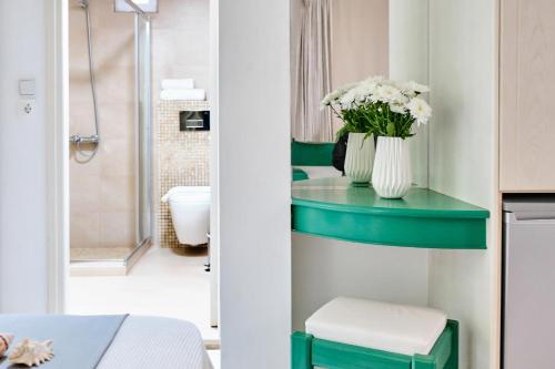 a bathroom with a green table with a vase of flowers at Villa Mare Monte ApartHotel in Malia