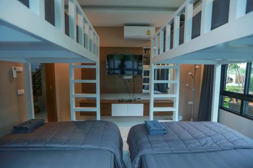 a bedroom with two bunk beds and a tv at Summer Sense Sattahip Pool Villa in Sattahip