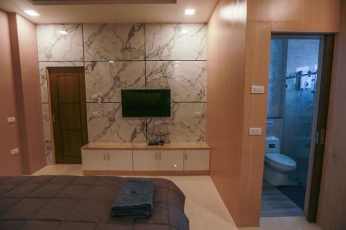 a bedroom with a bed and a television and a toilet at Summer Sense Sattahip Pool Villa in Sattahip