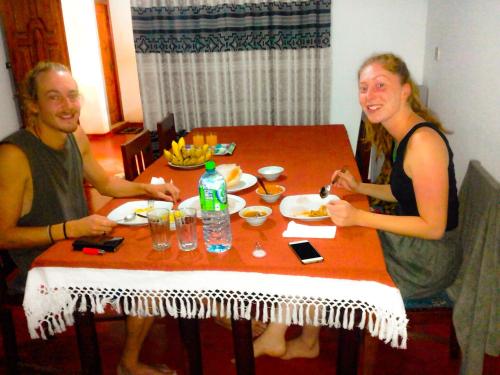 two people sitting at a table eating food at Chandra Holiday Home in Dickwella