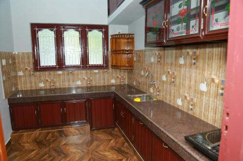 a kitchen with wooden cabinets and a counter top at JEEVAN HOMESTAY kovalam in Kovalam