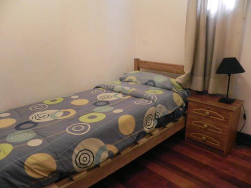 a small bedroom with a bed and a dresser at Lemuria Hostel in Valparaíso