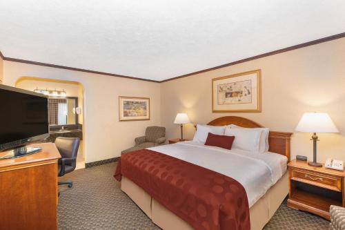 a hotel room with a bed and a flat screen tv at Ramada by Wyndham Midtown Grand Island in Grand Island