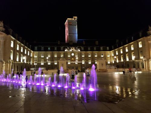 uma fonte de água em frente a um edifício à noite em Hôtel Montchapet Dijon Centre em Dijon