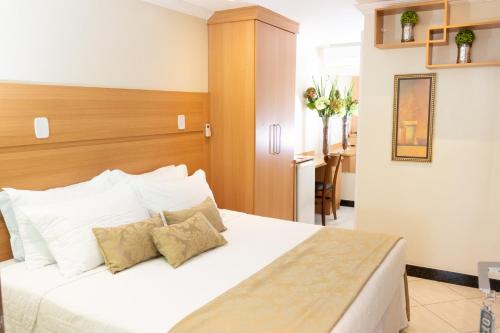 a bedroom with a large white bed with two pillows at Hotel Cravo e Canela in Campos dos Goytacazes