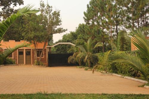 a house with a brick driveway and palm trees at Saltek Forest Cottages in Masindi
