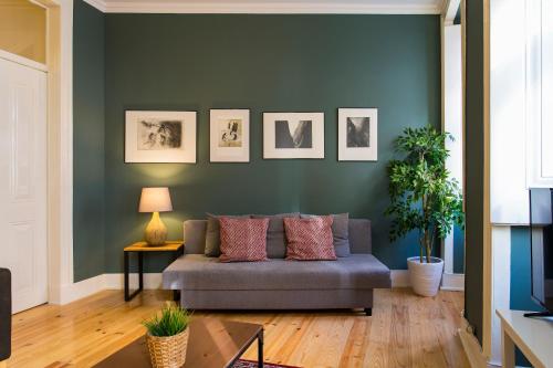 a living room with a couch and a green wall at Glória by Central Hill Apartments in Lisbon