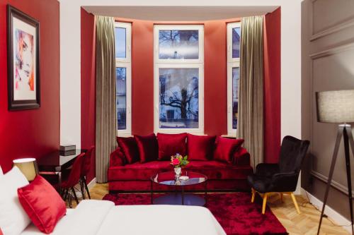 uma sala de estar vermelha com um sofá vermelho e janelas em Kings City - Blich Apartment em Cracóvia