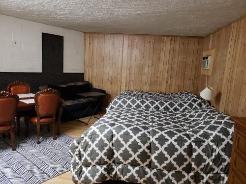 a bedroom with a black and white bed and a table at Caravan Motel in Fort Saint John