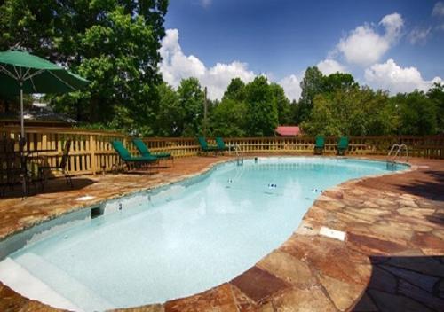 a large swimming pool with chairs and an umbrella at The Smoke House Lodge in Monteagle