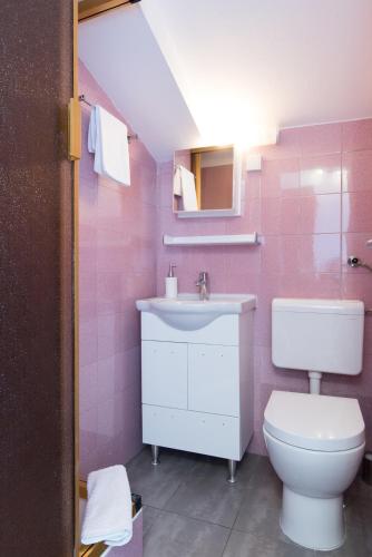 a pink bathroom with a sink and a toilet at Beach Guesthouse Mediteran in Podstrana