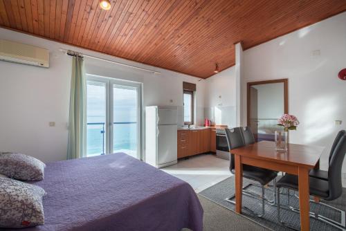 a bedroom with a bed and a table and a kitchen at Beach Guesthouse Mediteran in Podstrana