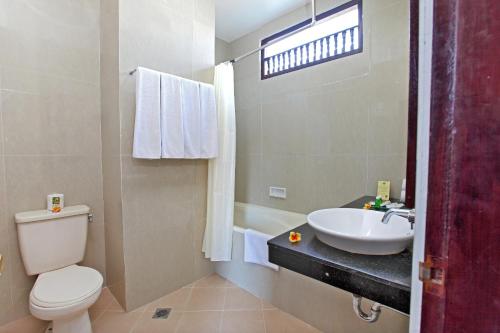 a bathroom with a sink and a toilet and a tub at Adi Dharma Hotel Kuta in Kuta